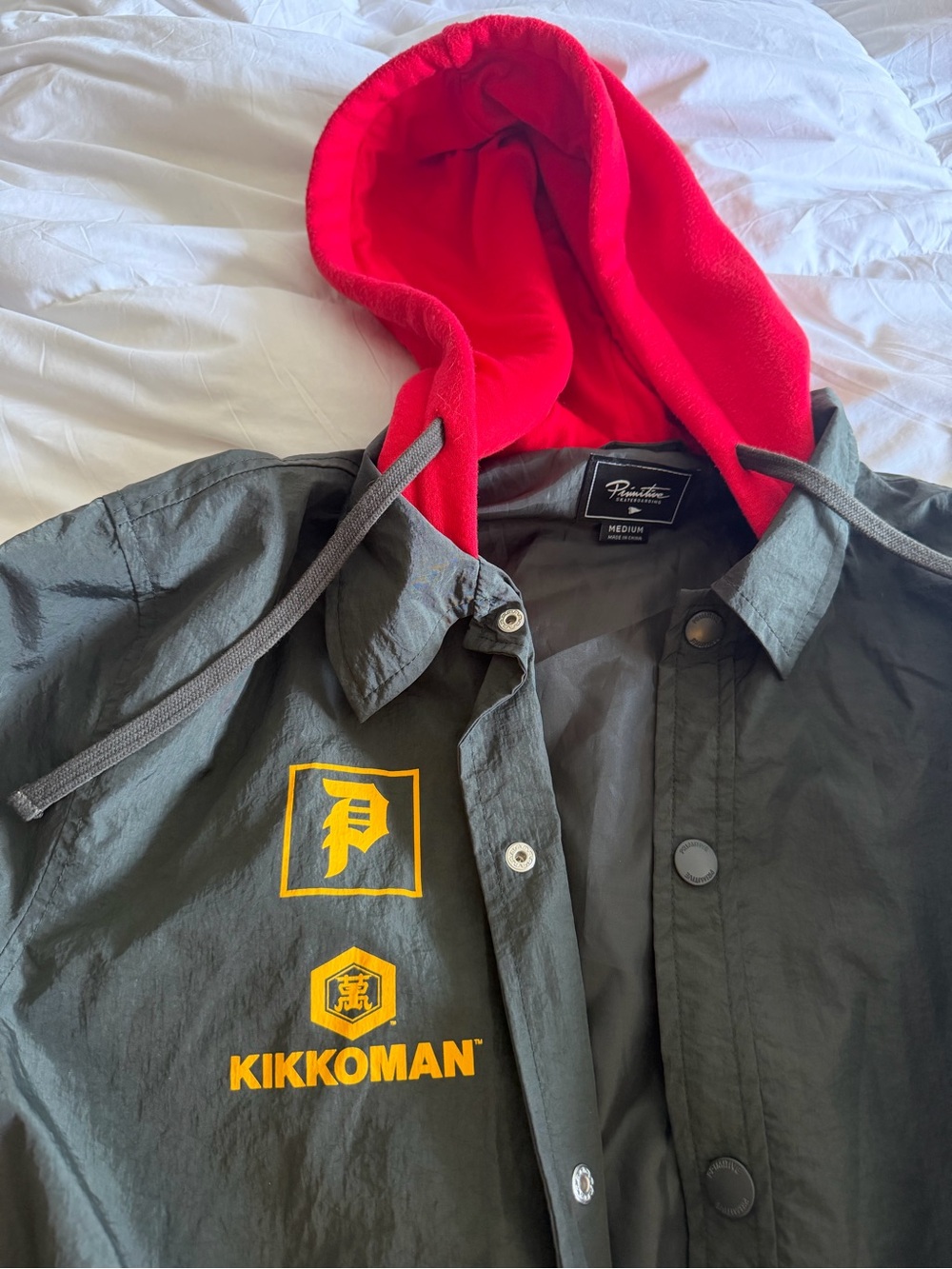 Primitive x Kikkoman Windbreaker Jacket with Red Hood and Yellow Logos